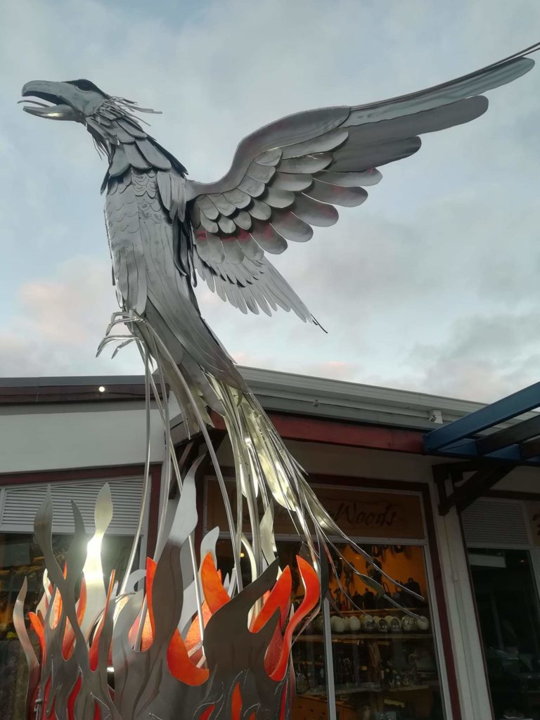 High grade 316 stainless steel Phoenix with resin flames , on a burned tree stump .